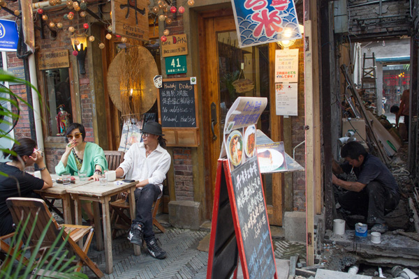 Customers sitting outside a cafe built after the renovation of an old house in Shanghai. An increasing number of young well off people in the city like small and high end units because they spend more time outside than at home. [Photo/China Daily]