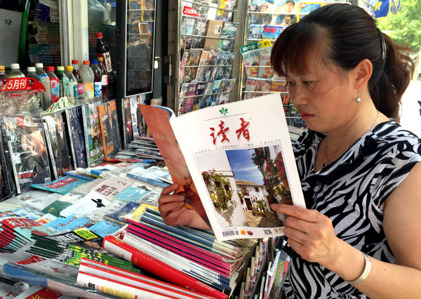 A reader checks the latest edition of Readers at a newspaper stand in Beijing on Wednesday. The popular magazine sells more than 200,000 copies of each edition. [Photo/China Daily]