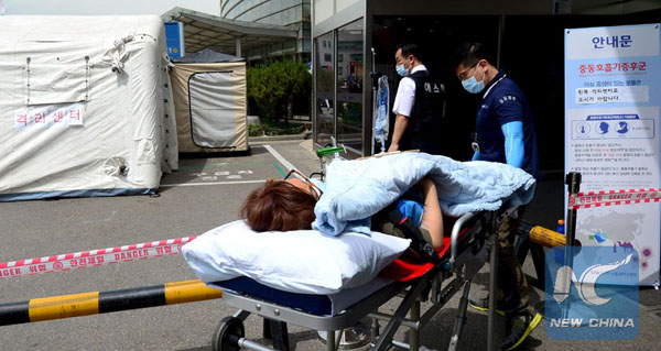 Hospital workers tend to a woman on a stretcher, who is believed to be infected with Middle East Respiratory Syndrome (MERS), in a quarantine area set up in a hospital in Seoul, South Korea, June 1, 2015. The first two deaths from the Middle East Respiratory Syndrome (MERS) infection were reported in South Korea on Tuesday. [Photo/Xinhua]