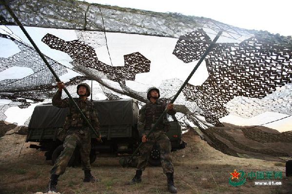  Two soldiers set up a camouflage net before the drill. 