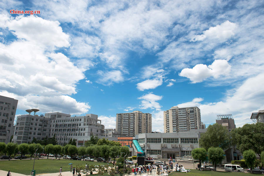 The sky above Capital Normal University in downtown Beijing is a crystal-clear blue on Thursday, June 11, 2015, after days of thunderstorms. Sunshine piercing through the white clouds brings a summery look to everything in the city below. [Photo by Chen Boyuan / China.org.cn]