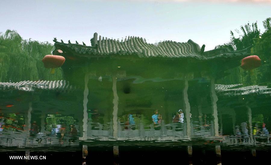 This inverted photo shows a reflection of vistors at the Baotu Spring scenic spot in Jinan, capital of east China's Shandong Province, June 22, 2015. The famous scenery spot Baotu Spring stopped spouting due to low underground water level during the Dragon Boat festival holiday. [Xinhua]