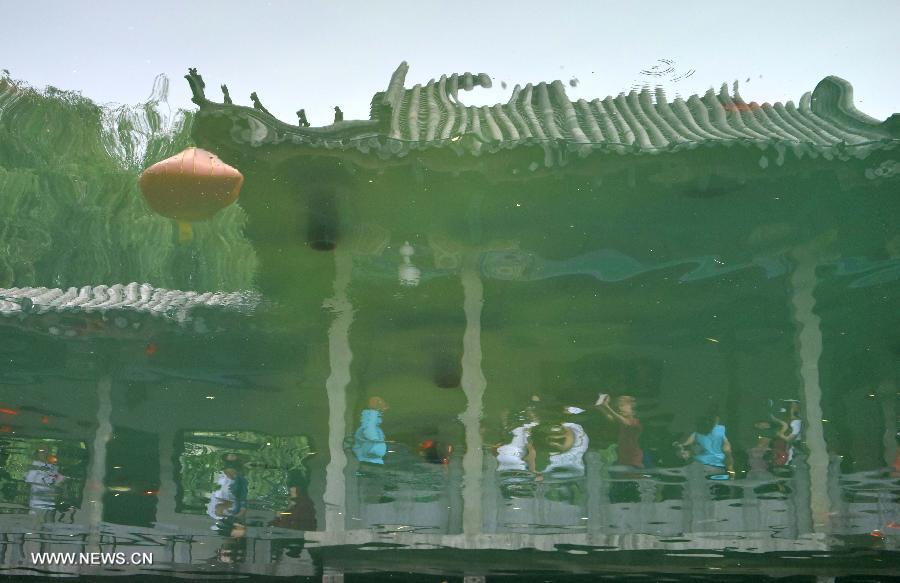 This inverted photo shows a reflection of vistors at the Baotu Spring scenic spot in Jinan, capital of east China's Shandong Province, June 22, 2015. The famous scenery spot Baotu Spring stopped spouting due to low underground water level during the Dragon Boat festival holiday. [Xinhua]