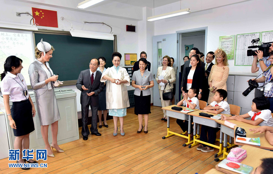 Chinese President Xi Jinping's wife Peng Liyuan (4th L, front) and Queen Mathilde of Belgium (2nd L, front) communicate with students from Beijing Experimental School for the Deaf in Beijing, capital of China, June 24, 2015.