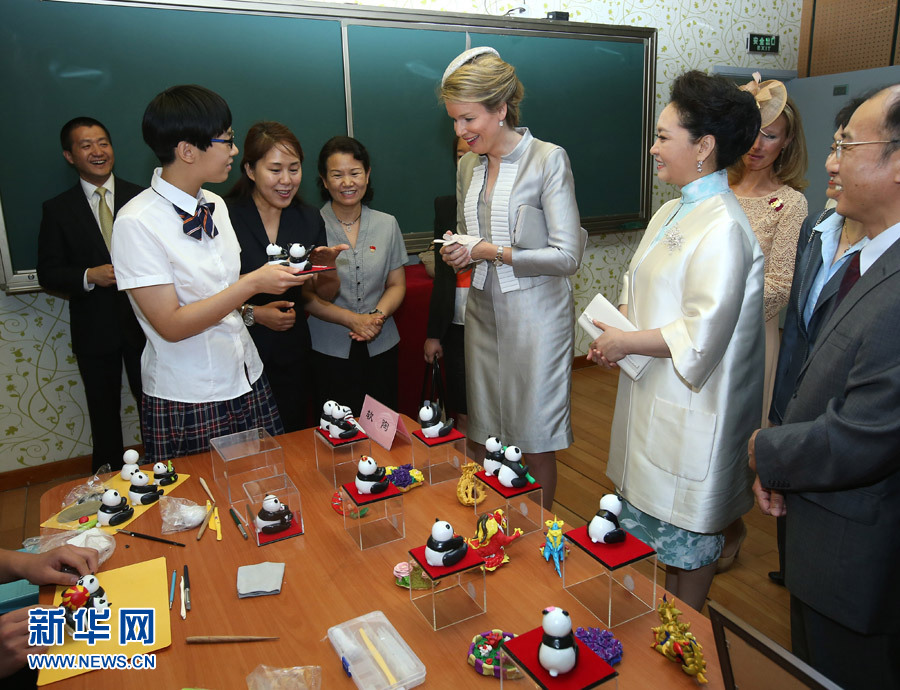 Chinese President Xi Jinping's wife Peng Liyuan (2nd R, front) and Queen Mathilde of Belgium (3rd R, front) look at pottery artworks by students from Beijing Experimental School for the Deaf in Beijing, capital of China, June 24, 2015.