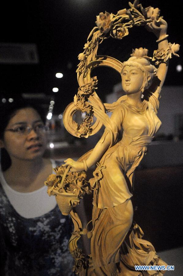 A woman looks at a wood sculpture displayed during a wood art show in Xianyou, southeast China's Fujian Province, June 25, 2015. A wood art show was held in Duwei Township of Xianyou in Fujian Province on Thursday. Duwei Township is home to nearly 1,000 wood carving workshops, and the local expertise in decorative wood carving has a history of almost 1,000 years. [Xinhua]