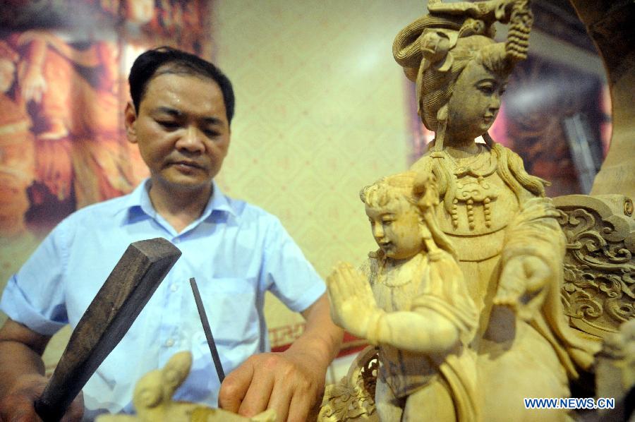 Artist Li Dinghua works on a wood sculpture during a wood art show in Xianyou, southeast China's Fujian Province, June 25, 2015. A wood art show was held in Duwei Township of Xianyou in Fujian Province on Thursday. Duwei Township is home to nearly 1,000 wood carving workshops, and the local expertise in decorative wood carving has a history of almost 1,000 years. [Xinhua]