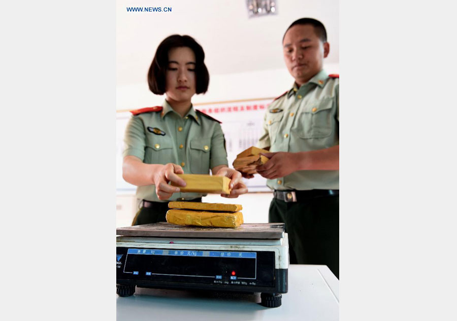 Zhang Liu (L) and her comrade prepare to weigh drugs they captured at border checkpoint of Mukang in Dehong Dai-Jingpo autonomous prefecture, Southwest China's Yunnan province, June 24, 2015. [Photo/Xinhua]