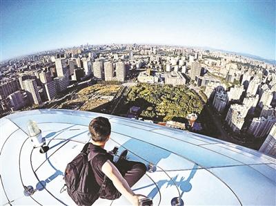 A man gets a bird's eye view of Beijing at the top of Wangjing SOHO. [Photo/Sina Weibo]