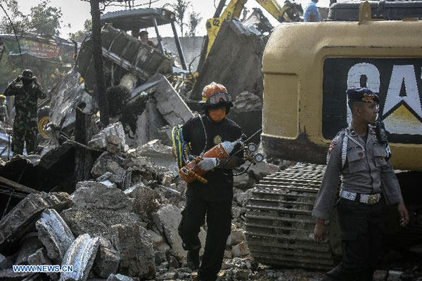 A firefighter and a policeman work at the crash site of an Indonesian military plane Hercules C-130 in the capital of North Sumatra province Medan, Indonesia, on June 30, 2015. 