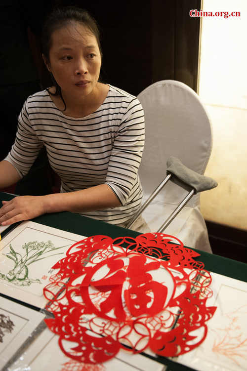Zhou Ziju, who works at a rural enterprise engaged in paper cutting in southwest China's Chongqing Municipality, showcases some of the works done by her colleagues at the launch ceremony of @Her Entrepreneurship Plan in Beijing on Tuesday, June 30, 2015. [Photo by Chen Boyuan / China.org.cn] 