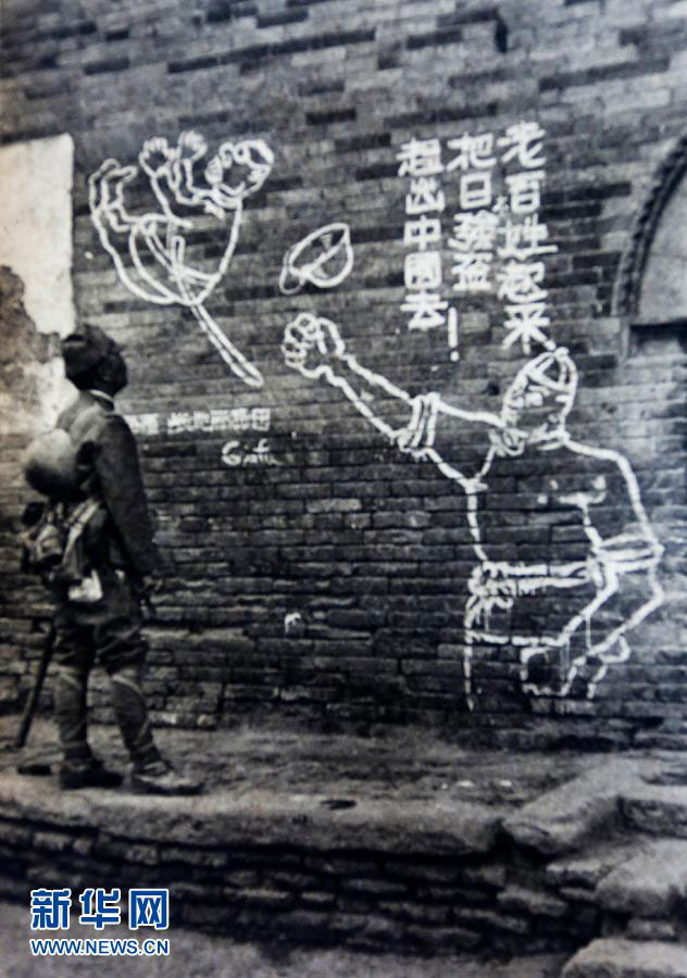 A Japanese soldier looks at a slogan calling for more civilians to join in the war against Japanese aggression in Hongtong County, northwest China's Shanxi province. The photo was taken by a Japanese military correspondent. [Photo: Xinhua]