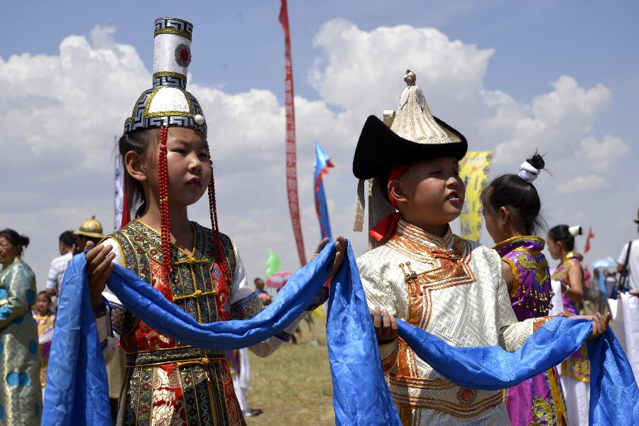 Children wearing traditional Mongolian costumes are seen during a Nadam fair in Urat Middle Banner, north China's Inner Mongolia Autonomous Region, July 4, 2015. Nadam is a mass traditional Mongolian festival where people celebrate harvests and pray for good luck. [Xinhua]