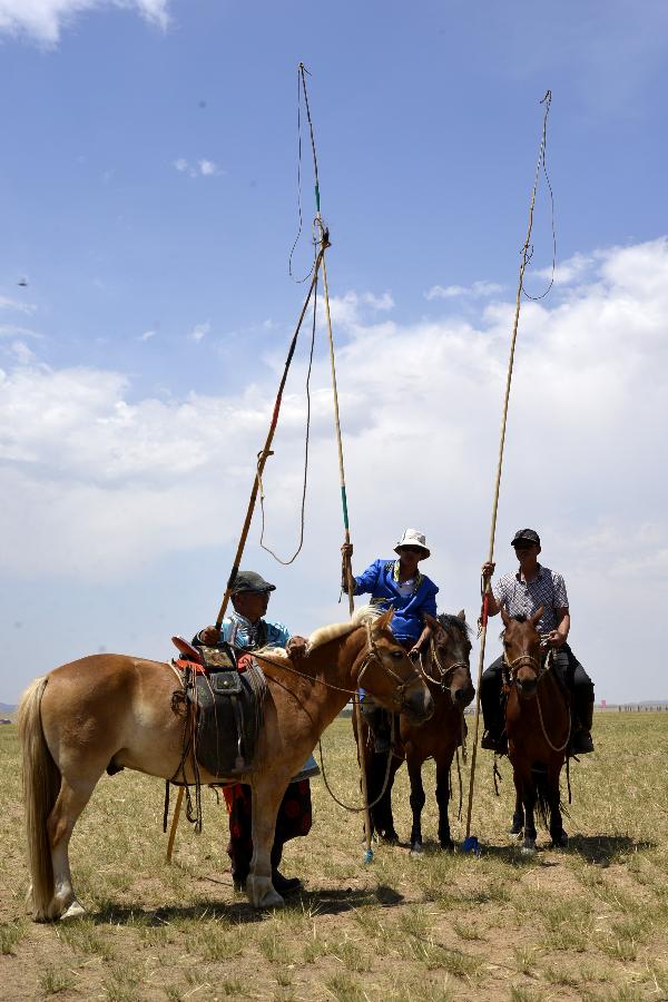 Participants wait to take part in horse racing during a Nadam fair in Urat Middle Banner, north China's Inner Mongolia Autonomous Region, July 4, 2015. Nadam is a mass traditional Mongolian festival where people celebrate harvests and pray for good luck. [Xinhua]