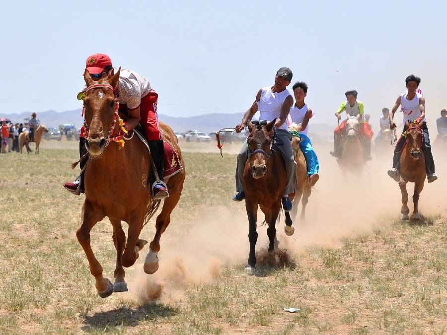 Participants take part in horse racing during a Nadam fair in Urat Middle Banner, north China's Inner Mongolia Autonomous Region, July 4, 2015. Nadam is a mass traditional Mongolian festival where people celebrate harvests and pray for good luck. [Xinhua]