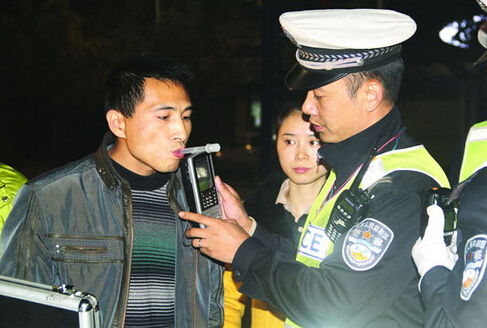 A traffic police officer uses a breathalyzer to test a driver for traces of alcohol.