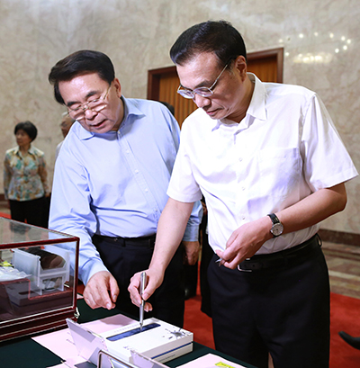 Premier Li Keqiang, accompanied by Bai Chunli, president of the Chinese Academy of Sciences, tries an electronic pen developed by the academy before sitting down for talks with leading scientists on the country's development of science. [Photo by Feng Yongbin/China Daily]
