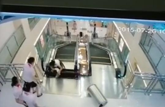 Screenshot from a surveillance video footage shows the moment when the woman falls into the gap that suddenly appeared on the escalator. She is seen holding her son to save his life in a shopping mall in Jingzhou city in central China's Hubei province on July 26, 2015. [Photo: Xinhua] 