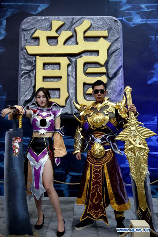 Models introduce an online game during the annual ChinaJoy exhibition, or China Digital Entertainment Expo and Conference, in Shanghai, east China, July 30, 2015. About 3,500 games developed by more than 700 enterprises from home and abroad were displayed on the exhibition. [Xinhua]