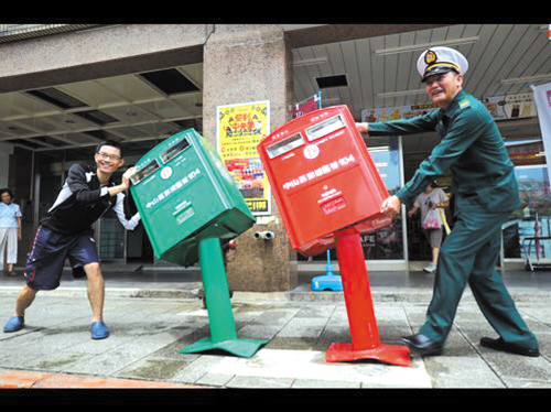 People pose with two letter boxes which were bent to one side by Super Typhoon Soudelor in Taipei, Taiwan, Aug 9, 2015.