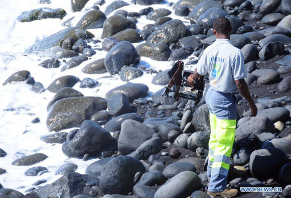 A searcher searches the Saint Andre Beach of France's overseas island La Reunion in the Indian Ocean, where the first piece of debris from the missing Malaysian Airlines flight MH370 was found, on Aug. 10, 2015. [Photo/Xinhua]
