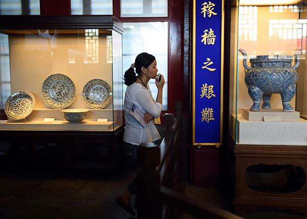 A visitor examines porcelains from the Ming Dynasty (1368-1644) during a three-month exhibition at the Palace Museum in Beijing in June. The porcelains on display are both perfect samples and restored ones from unearthed ceramic chips. [Jin Liangkuai/Xinhua]