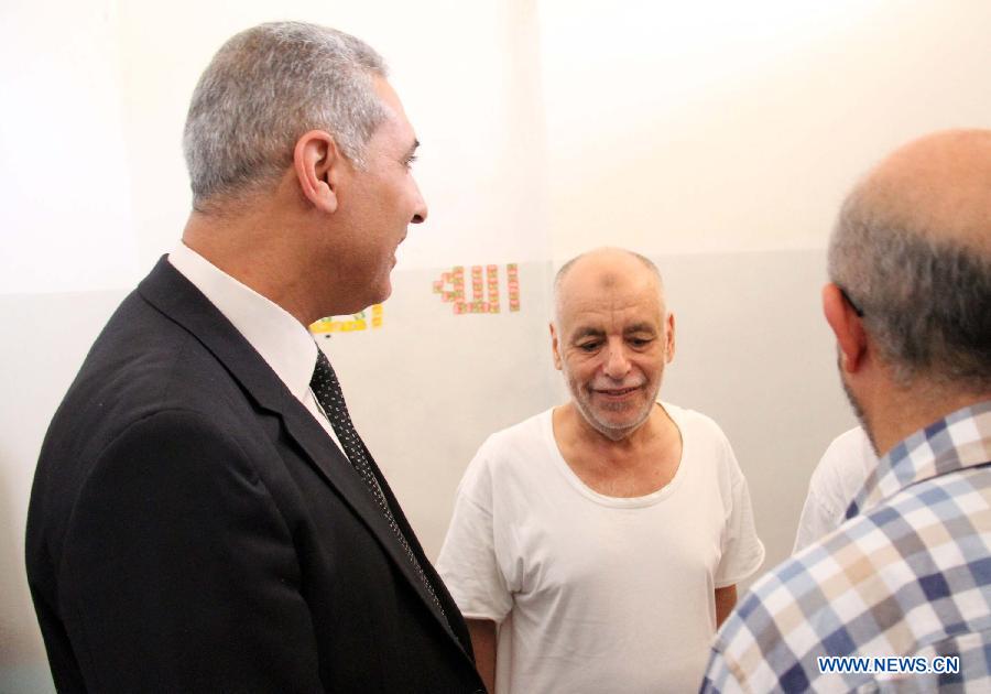 An official from Justice Ministry talks with Libya's former prime minister Baghdadi al-Mahmoudi (C) in al-Hadba prison in Tripoli, Libya, Aug. 10, 2015. An amateur video posted on social media showed Saadi blindfolded while a group of people beat and insulted him. Libyan Attorney General last week issued a decision to investigate the video and identify the people shown torturing Saadi in the video. [Photo/Xinhua]