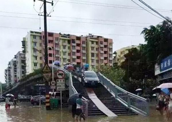 The car makes its way off the footbridge in Fuzhou after the flooding on Sunday. [Photo/qq.com]