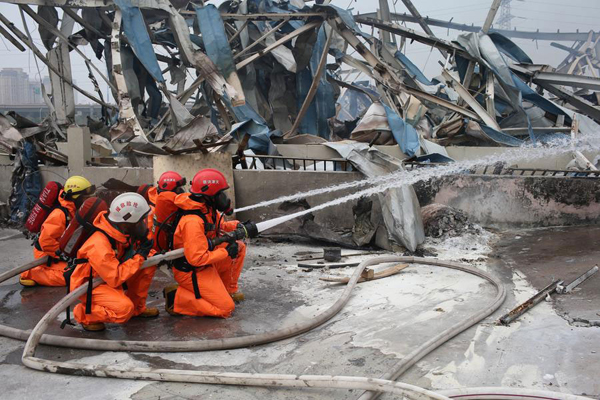 Firefighters in chemical protective clothing work at the site of the explosion in North China's Tianjin on Aug 15, 2015. [Photo/Xinhua]