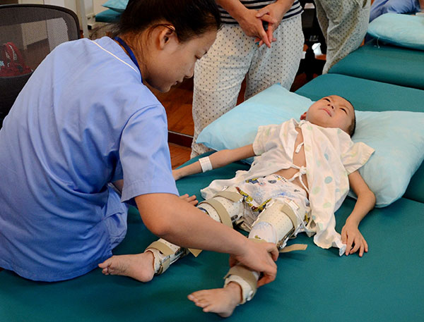 A 6-year-old boy who underwent surgery for brittle bone disease is cared for by a nurse. CHEN WEN/CHINA NEWS SERVICE/CHINA DAILY 