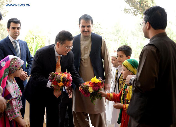 Chinese Ambassador to Afghanistan Deng Xijun (3rd L) receives flowers from Afghan children in Kandahar province in southern Afghanistan, Aug. 30, 2015. [Photo/Xinhua]