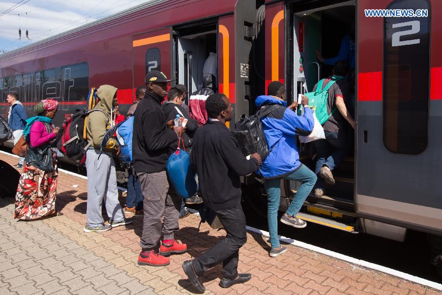 Illegal migrants traveling to Germany get on a train bound for Munich at a railway station near Austrian border in Hegyeshalom, Hungary, on Sept. 6, 2015. Germany is bracing for an unprecedented influx of up to 800,000 asylum seekers this year as Europe deals with its biggest migrant crisis since the Second World War. [Xinhua]