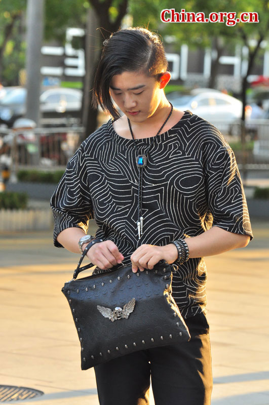 A stylish man wearing a string tie and carrying a skull bag stands on a Sanlitun street on Sept. 6, 2015. [Photo by GuoYiming/China.org.cn]
