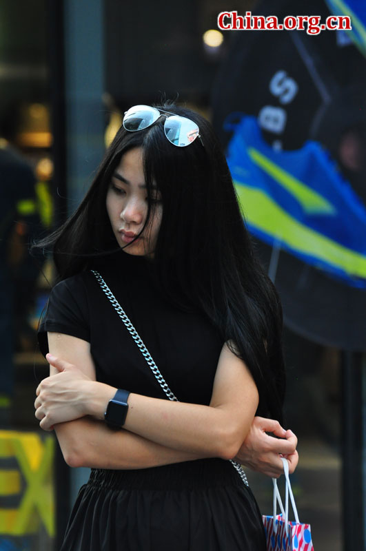 A chic woman wearing a pair of aviator sunglasses stands on a Sanlitun street on Sept. 6, 2015. [Photo by GuoYiming/China.org.cn]