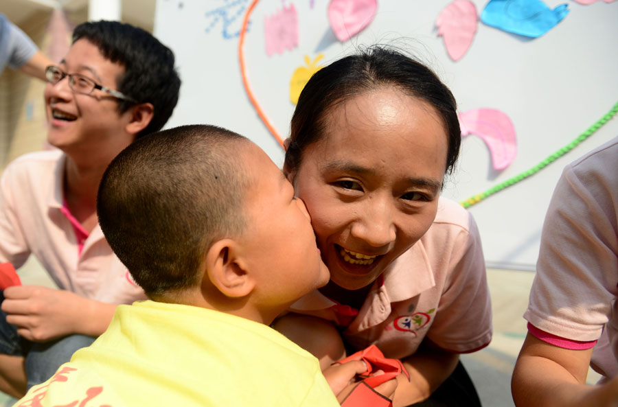 An autistic child kisses his teacher before Chinese Teacher's Day at Zhiai Yangguang Autism Rehabilitation Center in Hefei, capital of east China's Anhui Province, Sept. 9, 2015. China's Teacher's Day falls on Sept. 10 every year. [Xinhua]