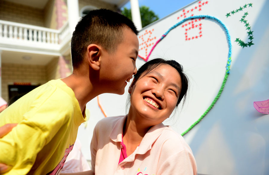 An autistic child kisses his teacher before Chinese Teacher's Day at Zhiai Yangguang Autism Rehabilitation Center in Hefei, capital of east China's Anhui Province, Sept. 9, 2015. China's Teacher's Day falls on Sept. 10 every year. [Xinhua]