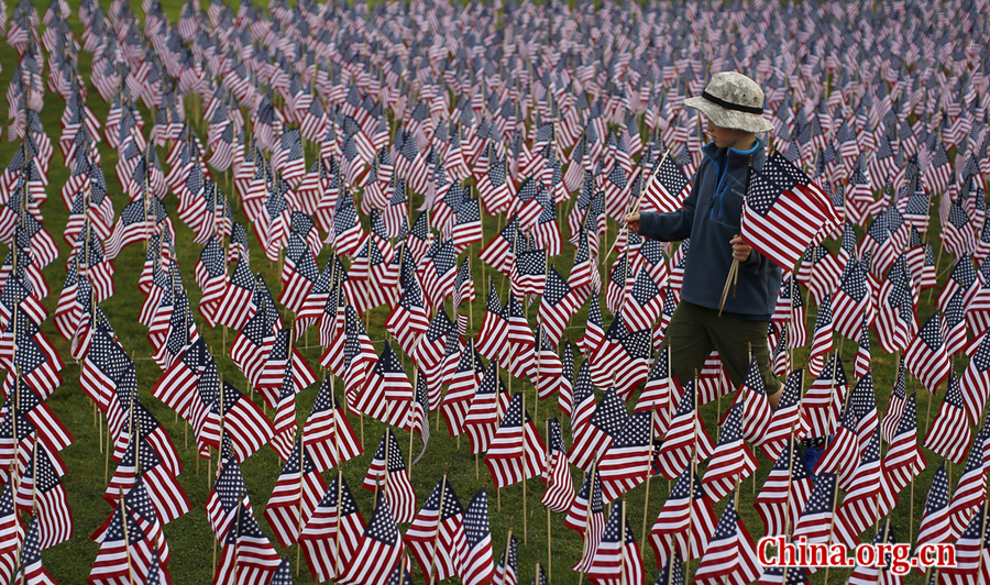 A boy walks among some of the 3,000 flags placed in memory of the lives lost in the September 11, 2001 attacks, at a park in Winnetka, Illinois, September 10, 2015. On Friday people will mark the 14th anniversary of the 9/11 attacks. [Photo/China.org.cn] 