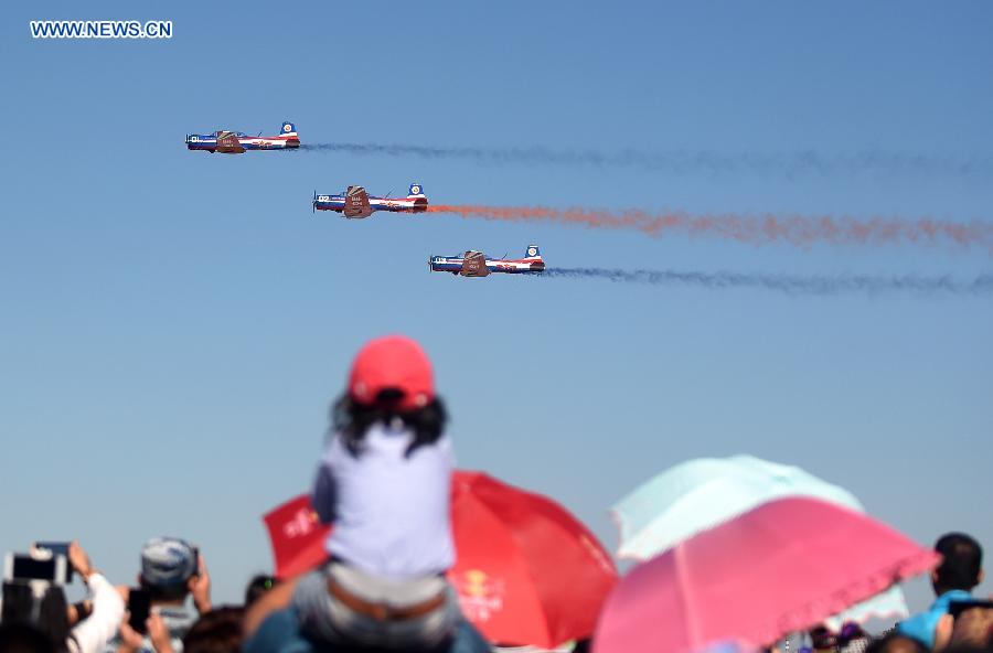 People watch the performance of the 'Tianzhiyi' aerobatic aircrafts from the Aviation University of Air Force at the Dafangshen Airport in Changchun, capital of northeast China's Jilin Province, Sept. 10, 2015. The Aviation Open Day of the Air Force of the CPLA and the opening ceremony for the Aviation University of Air Force was held here on Thursday. [Xinhua]