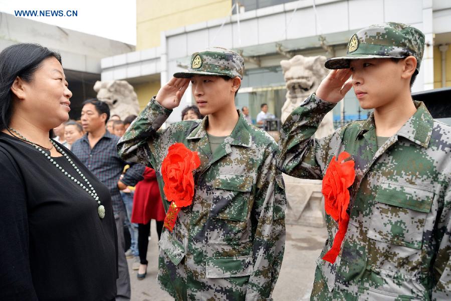 Twin brothers Jiang Zihao (C) and Jiang Zihang (R), who both are fresh army recruits, salute to their mother during a farewell ceremony in Handan, north China's Hebei Province, Sept. 10, 2015. The new recruits of the People's Liberation Army and paramilitary police force joined their units to fulfill their duty around the country recently. [Xinhua]