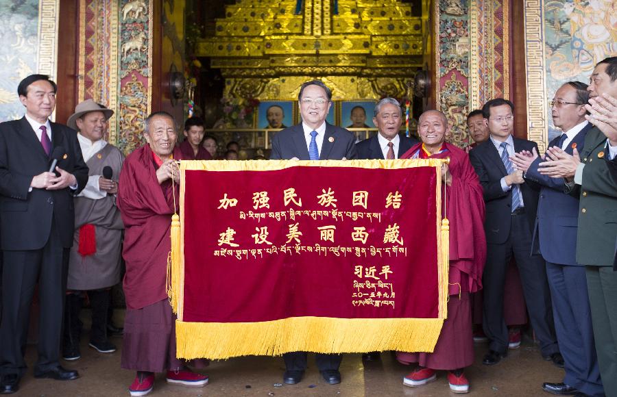 Yu Zhengsheng (C), chairman of the National Committee of the Chinese People's Political Consultative Conference, presents Tashilumpo Monastery with a banner inscribed with Chinese President Xi Jinping's words 'Enhancing ethnic unity, building a beautiful Tibet' in Xigaze, southwest China's Tibet Autonomous Region, Sept. 10, 2015. [Photo: Xinhua] 