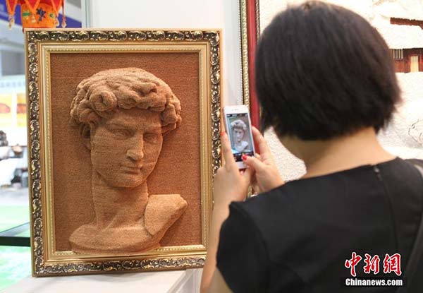 A woman takes a photo of a portrait of David at an art exhibition in Chongqing. [Photo/Chinanews.com]