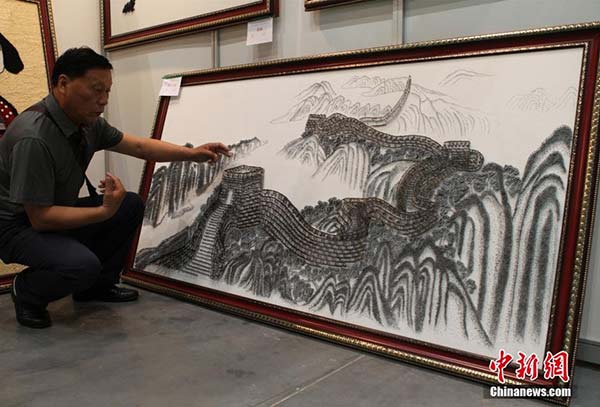 Artist Tang Jialu with his one piece of his work The Iron Great Wall. [Photo/Chinanews.com] 