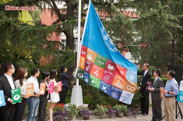 UNDP Deputy Country Director in China Patrick Haverman (R3) and Li Xi (R4) hoist a special UN flag attached to one featuring all the 17 SDGs on Wednesday, Sept. 16, 2015 in Beijing. [Photo by Chen Boyuan / China.org.cn]