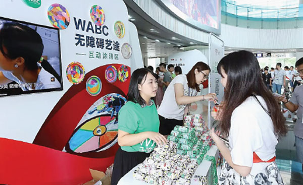 A Tencent employee, and charity supporter, explains to a visitor how to take part in Tencent's program. [Photo provided to China Daily]
