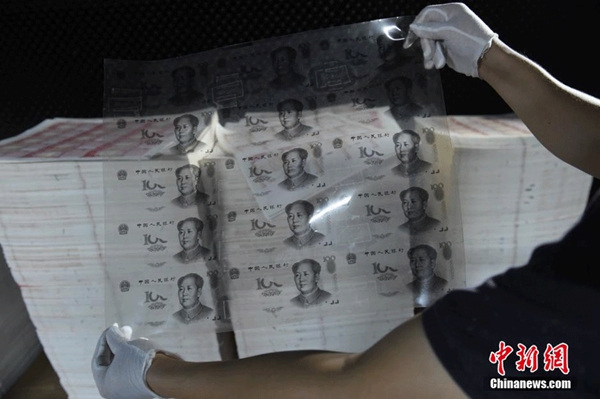 Police officers in Huizhou, in South China's Guangdong province, check out the rubber slab used for counterfeiting 100-yuan banknotes, on Sept 24, 2015. [Photo/chinanews.com]