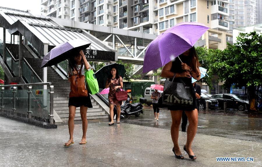 People walk under rain in Guangzhou, capital of south China's Guangdong Province, Oct. 4, 2015. Typhoon Mujigae, the 22nd typhoon this year, landed on South China's Guangdong Province on Sunday. [Photo/Xinhua]