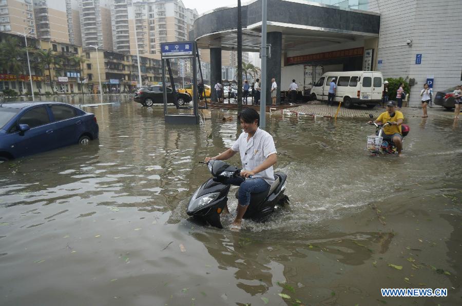 People ride on waterlogged road in Zhanjiang, south China's Guangdong Province, Oct. 4, 2015. Typhoon Mujigae, the 22nd typhoon this year, landed on South China's Guangdong Province on Sunday. [Photo/Xinhua]