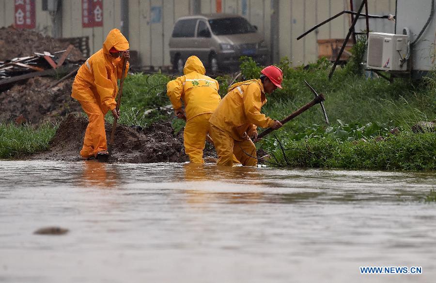 Workers work on waterlogged road in Haikou, south China's Hainan Province, Oct. 4, 2015. Typhoon Mujigae, the 22nd typhoon this year, has brought heavy rain in Haikou Sunday. [Photo/Xinhua]