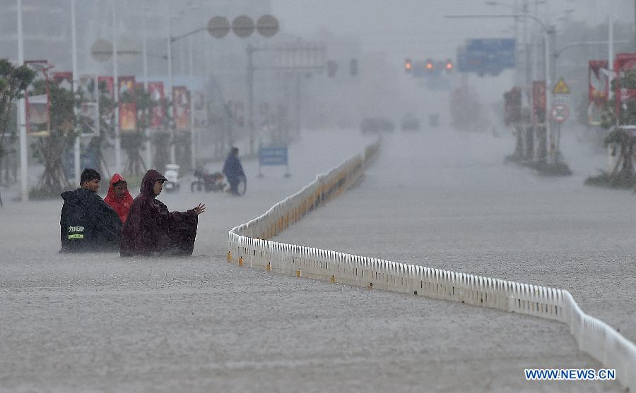 People walk on waterlogged road in Haikou, south China's Hainan Province, Oct. 4, 2015. Typhoon Mujigae, the 22nd typhoon this year, has brought heavy rain in Haikou Sunday. [Photo/Xinhua]