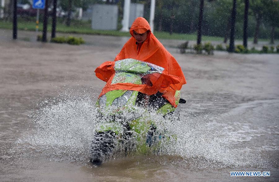 A man rides on waterlogged road in Haikou, south China's Hainan Province, Oct. 4, 2015. Typhoon Mujigae, the 22nd typhoon this year, has brought heavy rain in Haikou Sunday. [Photo/Xinhua]